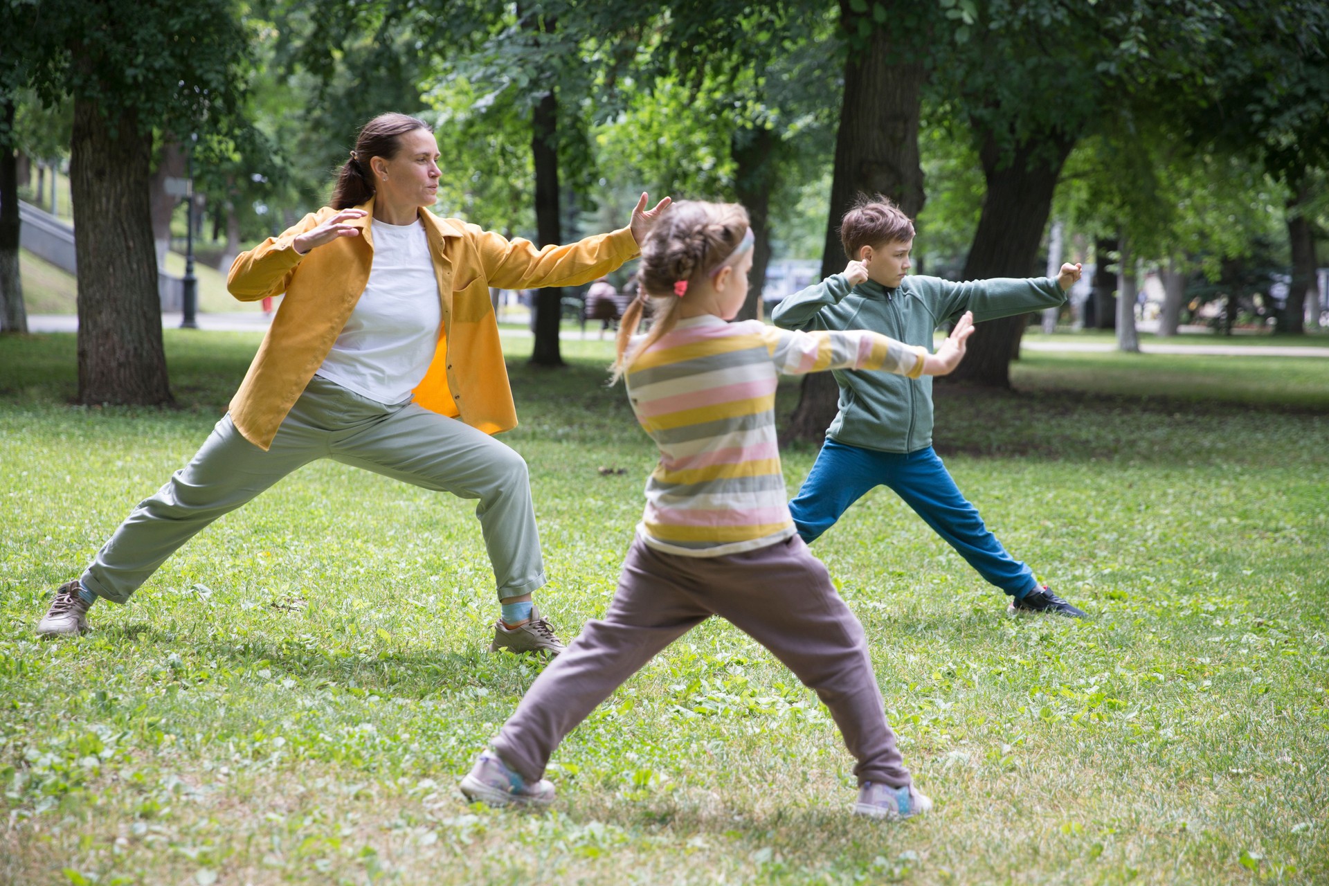 Familienmutter und zwei Kinder üben Tai Chi Chuan in einem Park. Chinesisches Management, Qi's Energie.