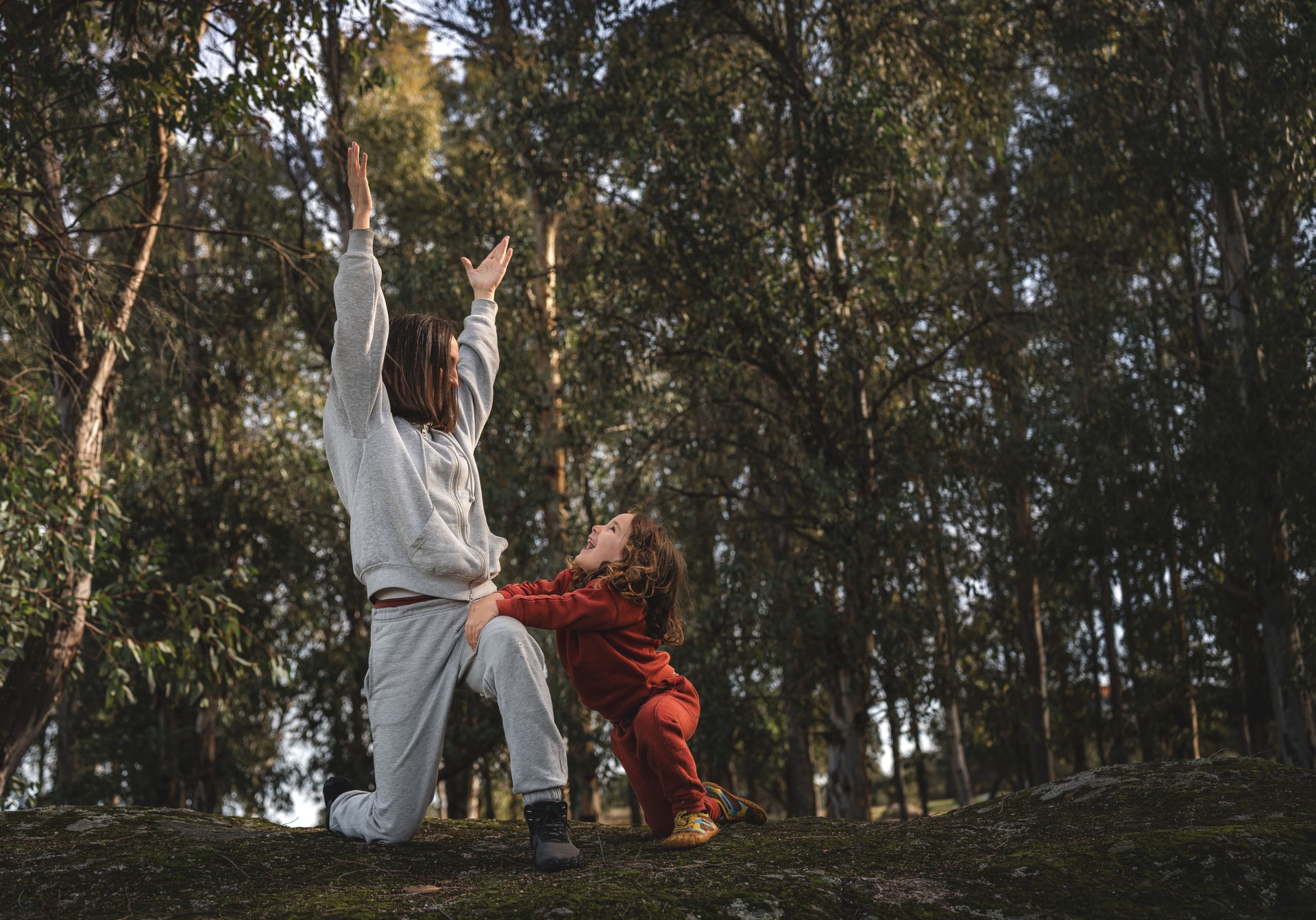 Eine Frau und ein Kind üben Yoga in einem Wald